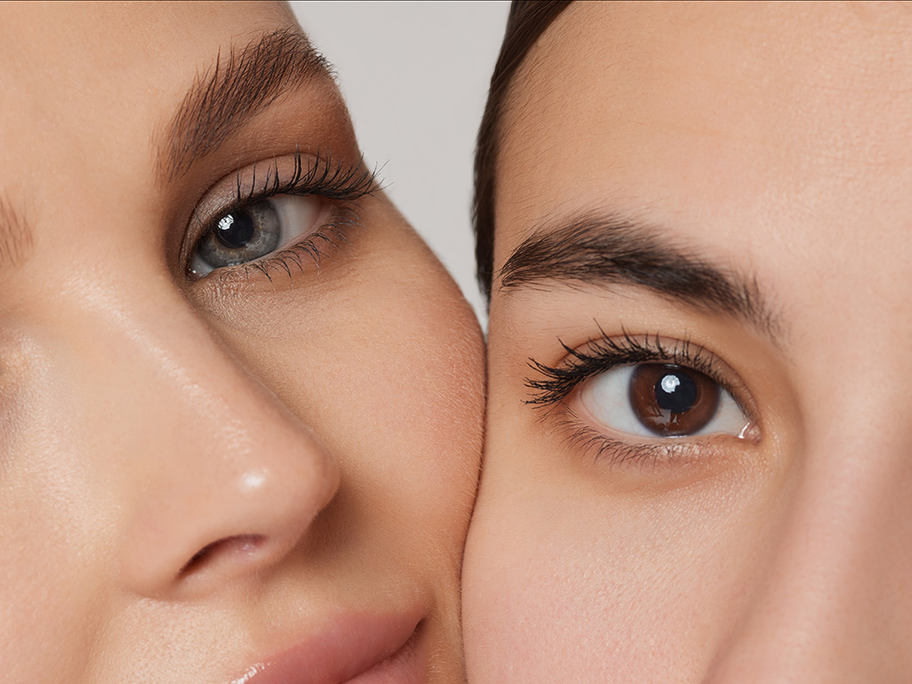 Blue and brown eyes. Vertical cropped portrait of young beautiful female couple.