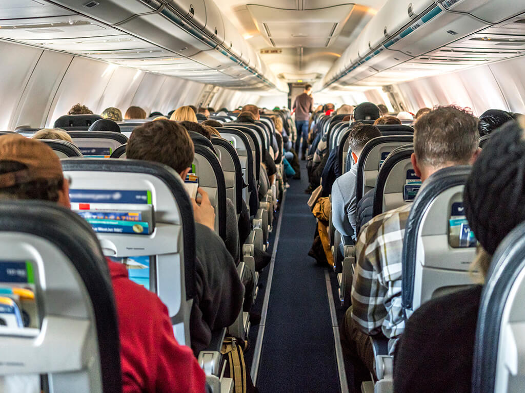 Passengers seated inside of a commercial passenger airplane. Travelers going across the globe.